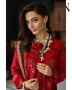 Woman in a red embroidered outfit holding a rose, wearing jewelry.