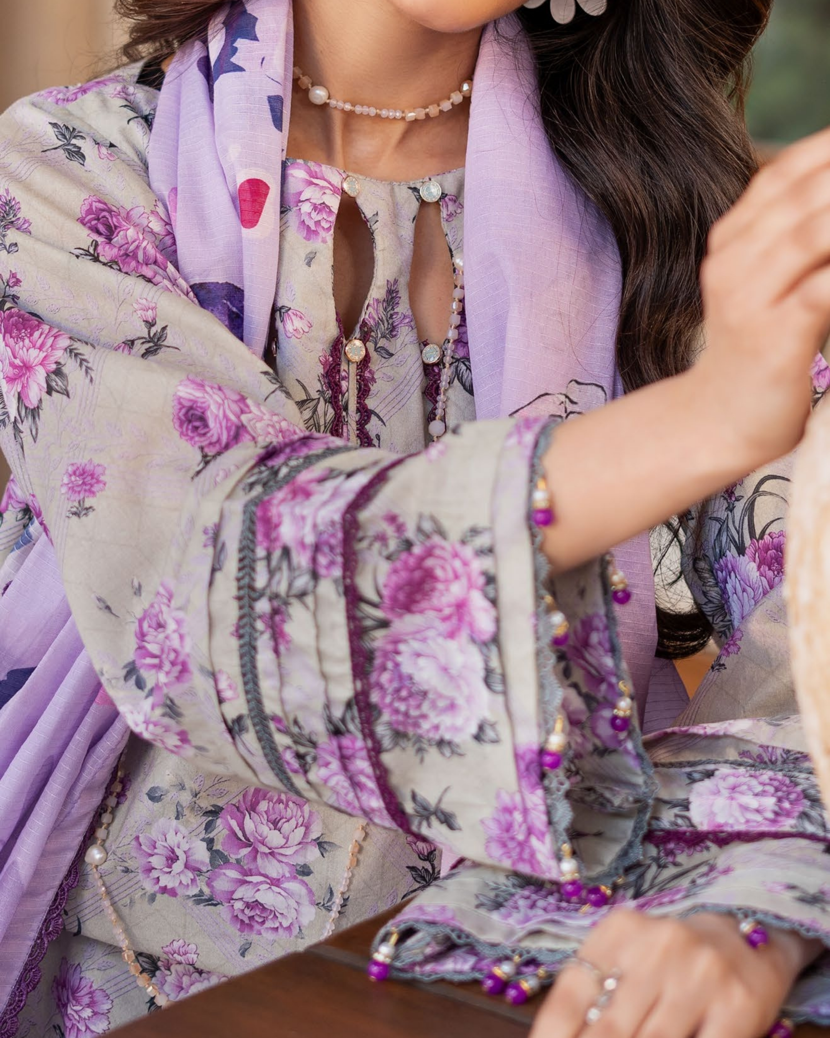 Woman wearing a floral dress with a matching scarf, focusing on the fabric details.