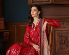 Woman in a red embroidered outfit sitting on a wooden chair in an elegant room.