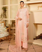 Woman in a pink traditional outfit standing in an elegant room with decorative elements.