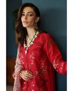Woman wearing a red embroidered outfit with jewelry against a dark background