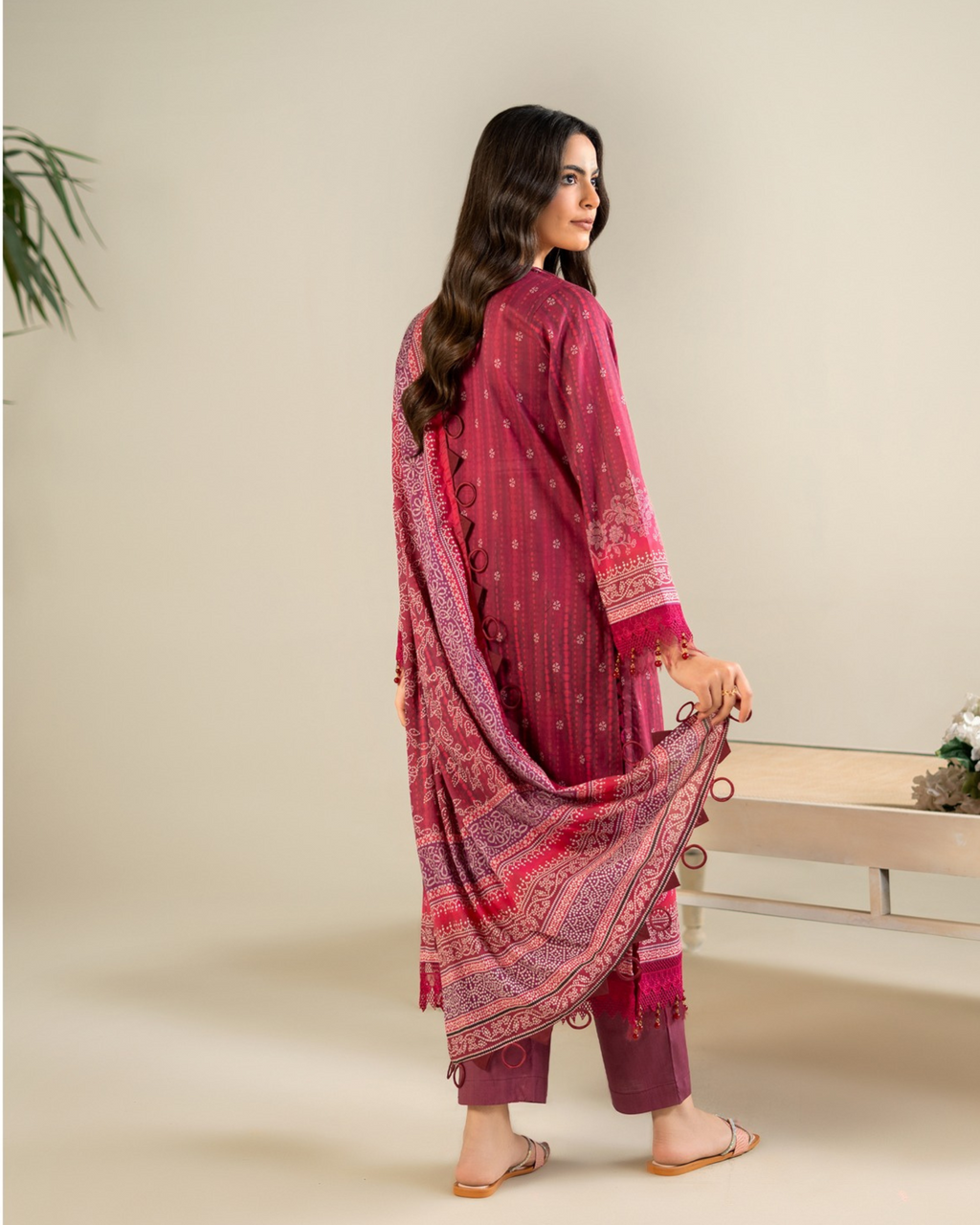 Woman wearing a pink traditional outfit with a matching dupatta on a beige background