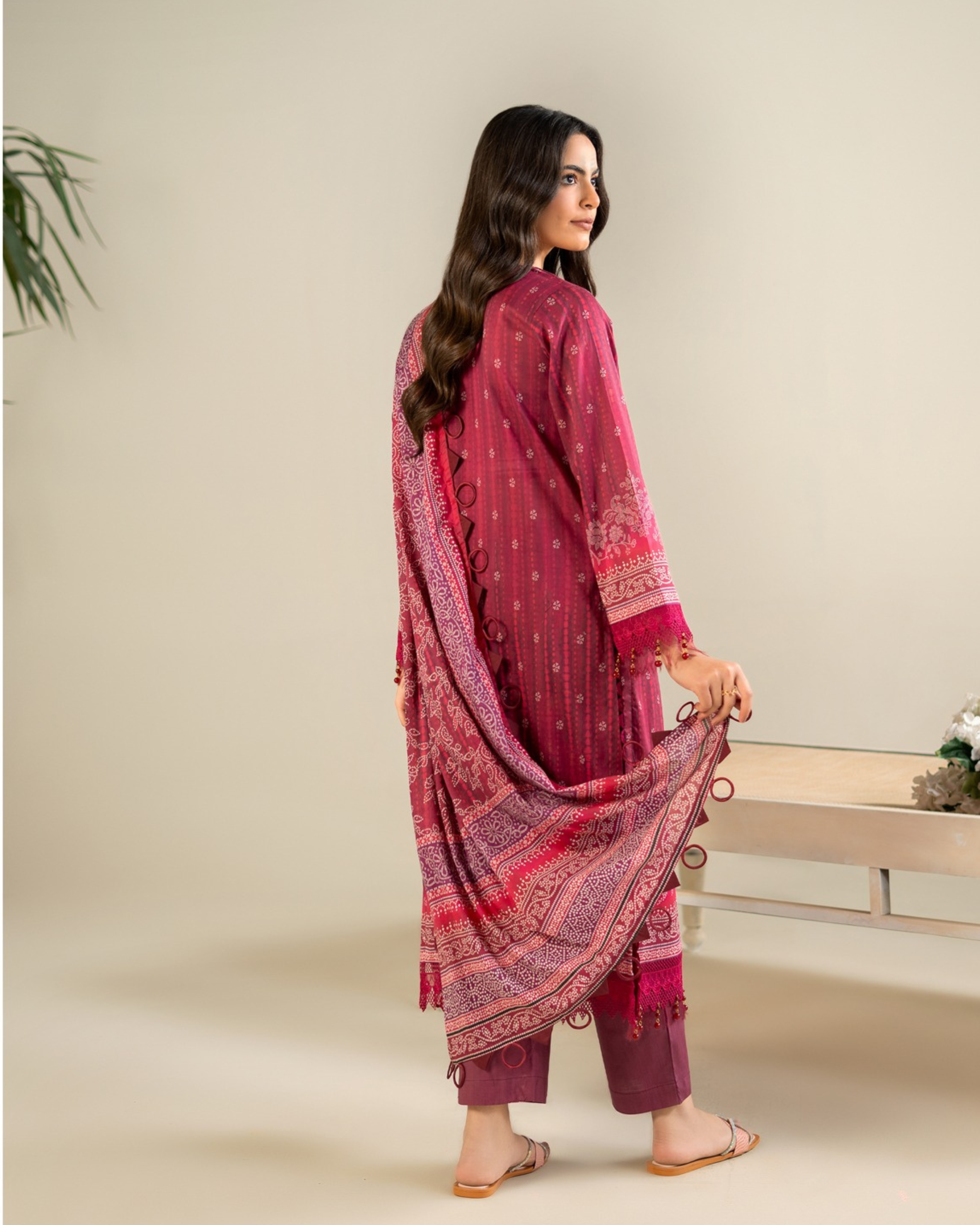 Woman wearing a pink traditional outfit with a matching dupatta on a beige background
