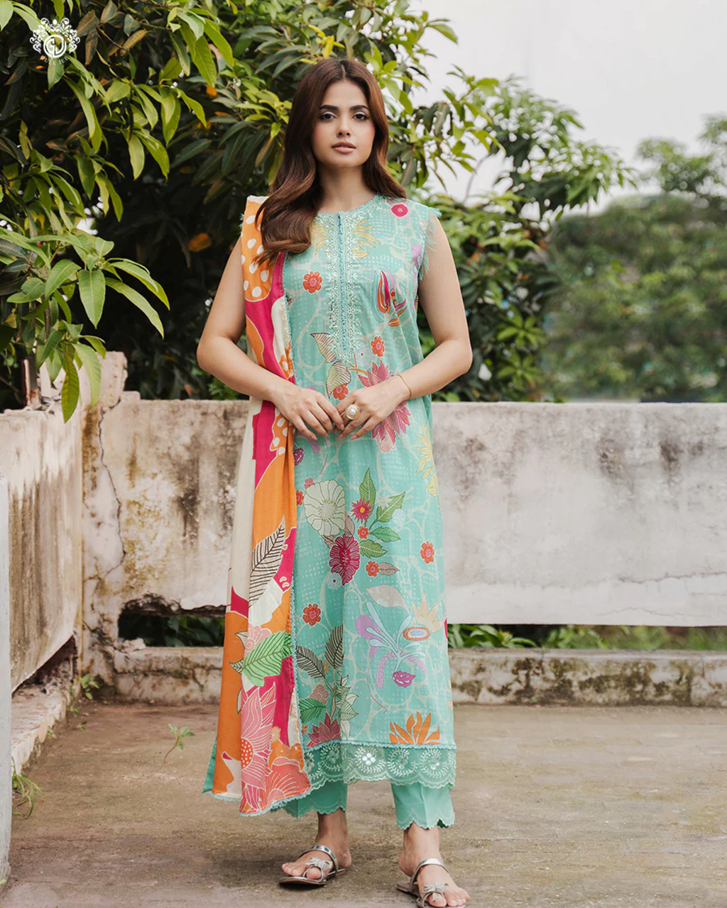 Woman wearing a colorful floral dress with a long scarf in an outdoor setting
