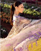 Woman in a floral dress with purple accents standing outdoors with plants in the background