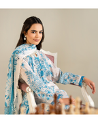 Woman in a blue and white floral outfit sitting on a chair.