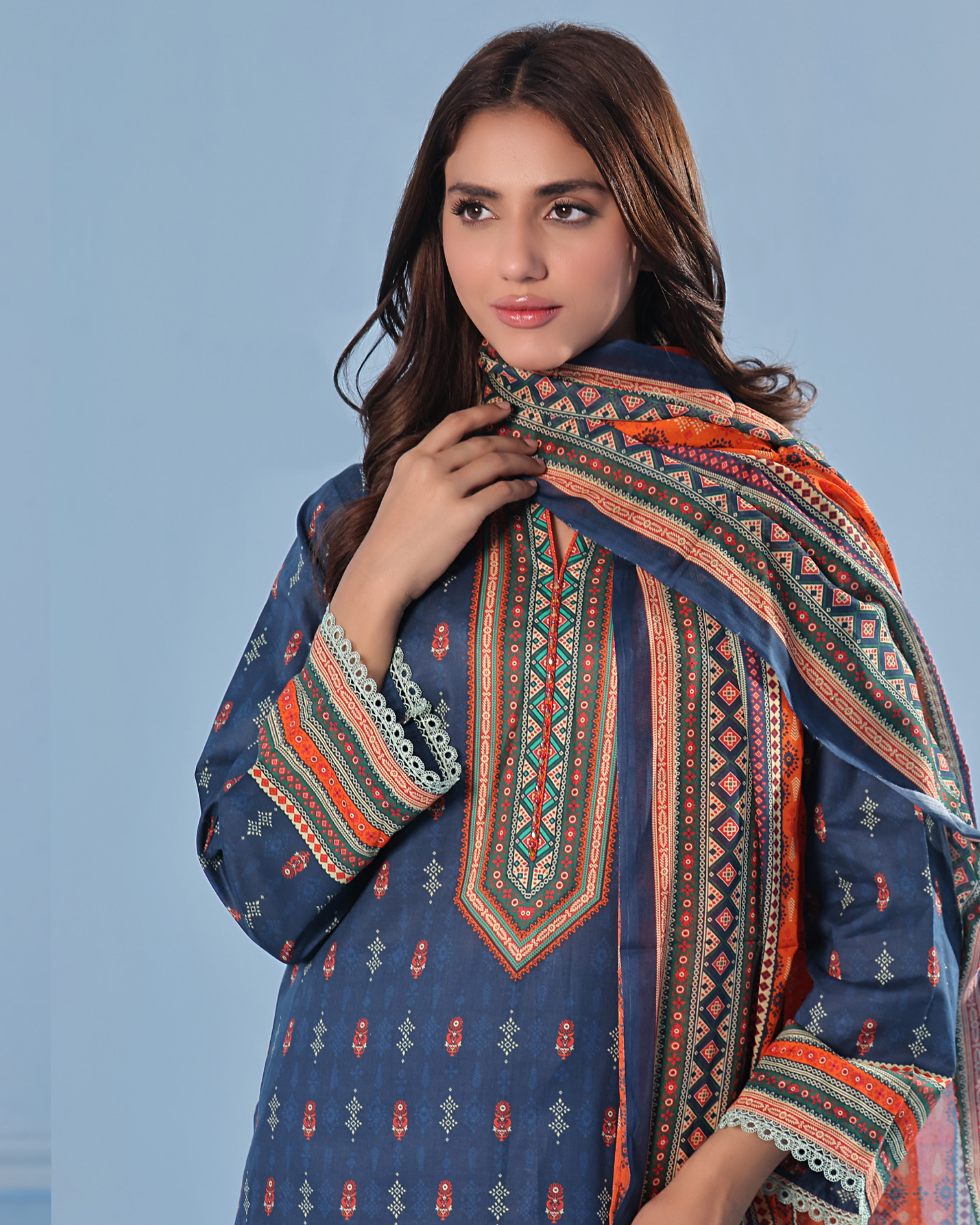 Woman wearing a patterned shawl against a blue background