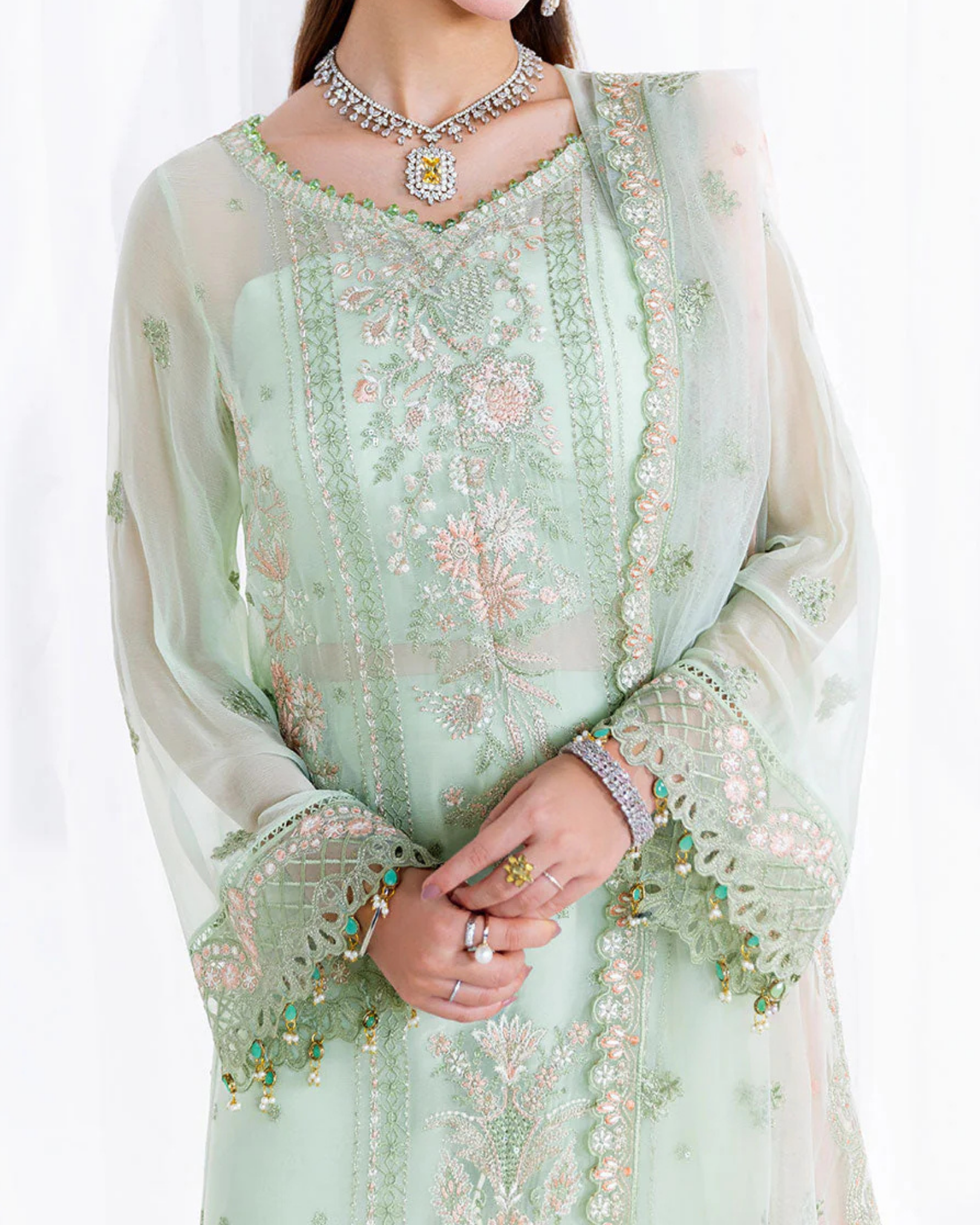 Light green embroidered traditional outfit with a white dupatta on a white background