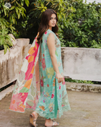 Woman wearing a colorful floral dress with a patterned dupatta outdoors.
