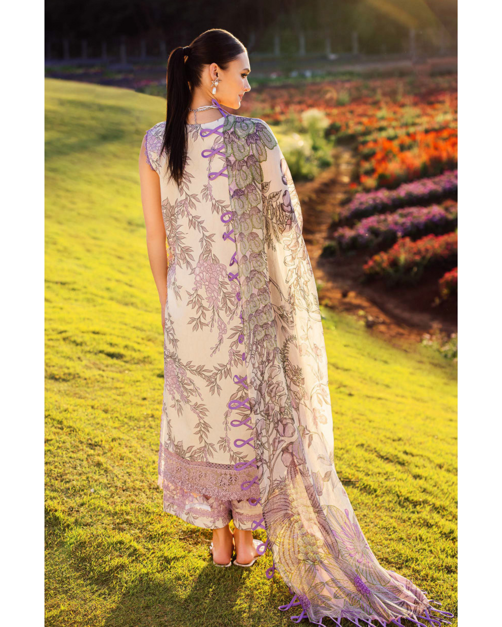 Woman in a floral dress standing in a field with colorful flowers in the background