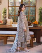 Woman in a floral outfit standing in a room with a wooden table and decorative items.