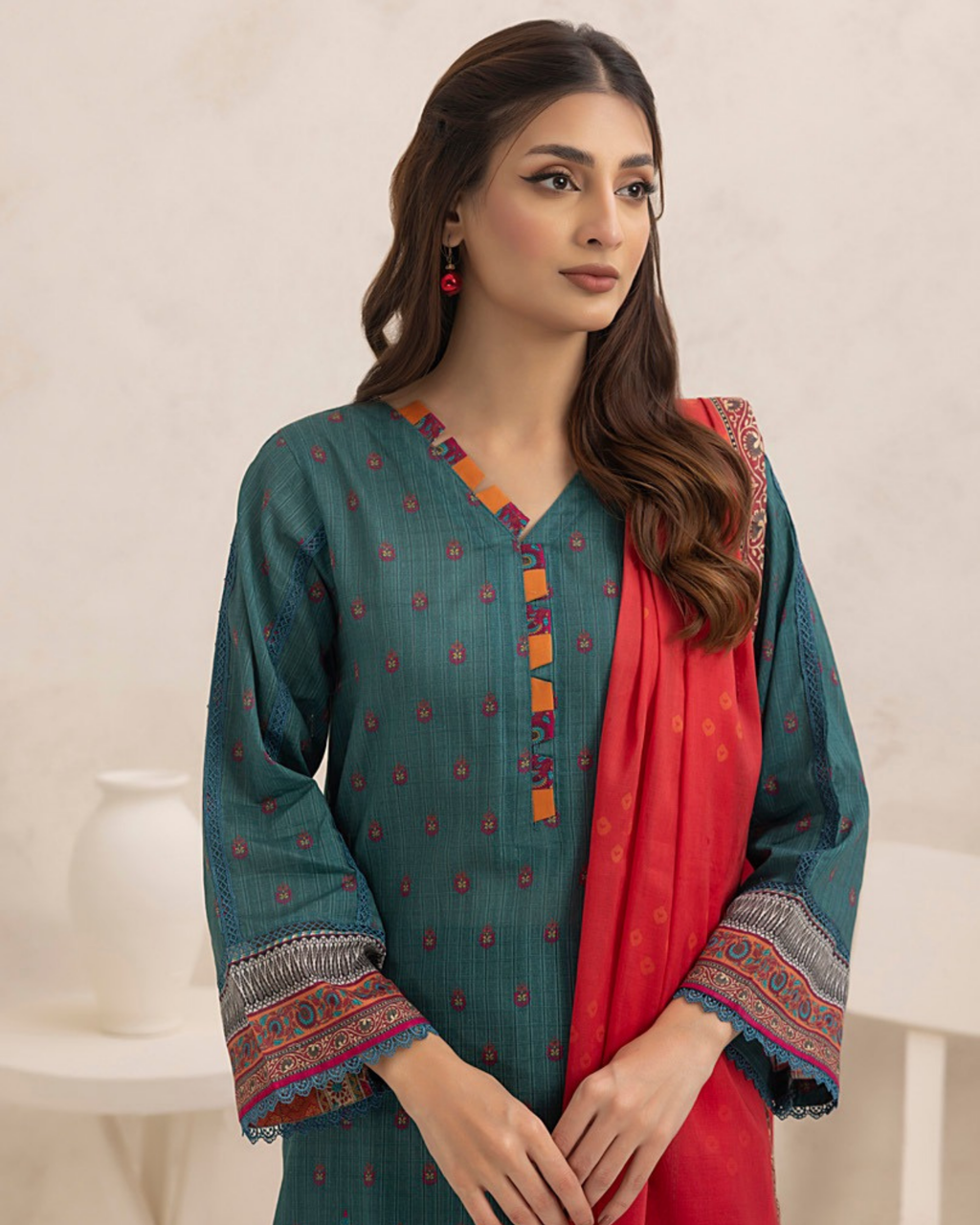 Woman wearing a teal and red traditional outfit with a plain background