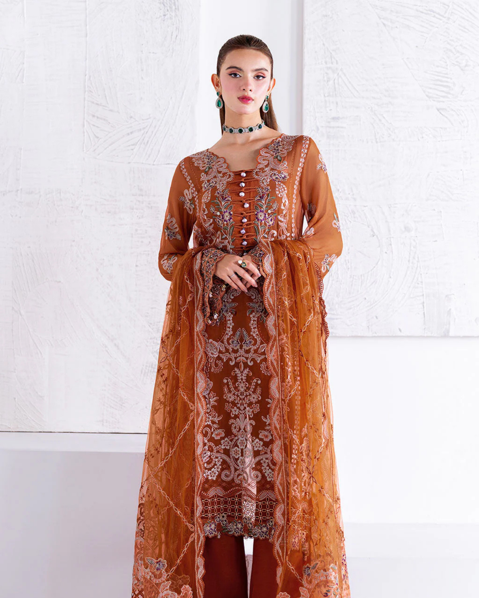 Woman wearing a brown embroidered outfit against a white background