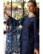Woman wearing a dark blue embroidered dress with floral sleeves indoors.