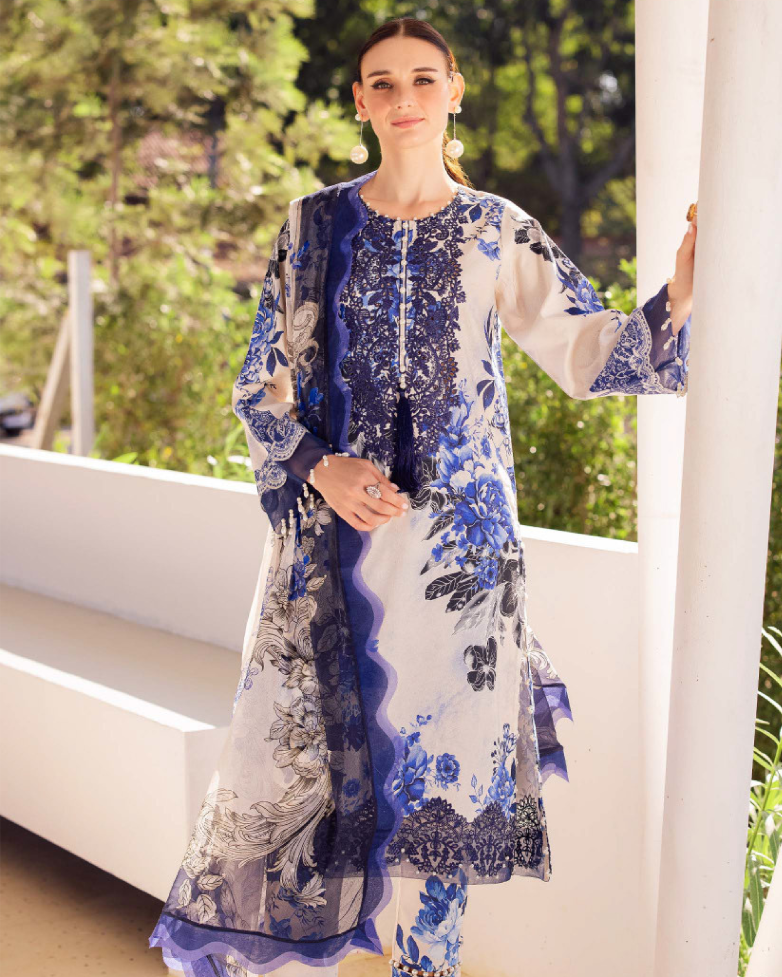 Woman wearing a blue and white floral dress standing outdoors.