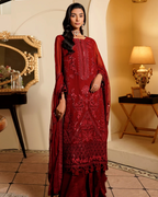 Woman in a red embroidered traditional outfit standing in an elegant room.