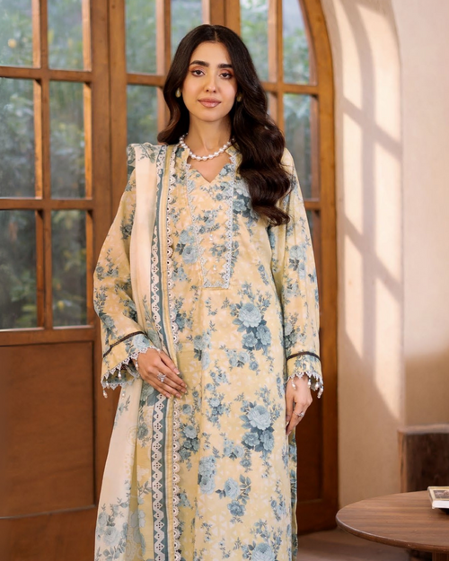 Woman in a floral dress standing in a room with large windows.
