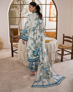 Woman in a floral outfit standing in a room with a table and chairs.