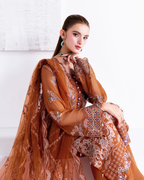 Woman wearing a brown embroidered traditional outfit against a white background