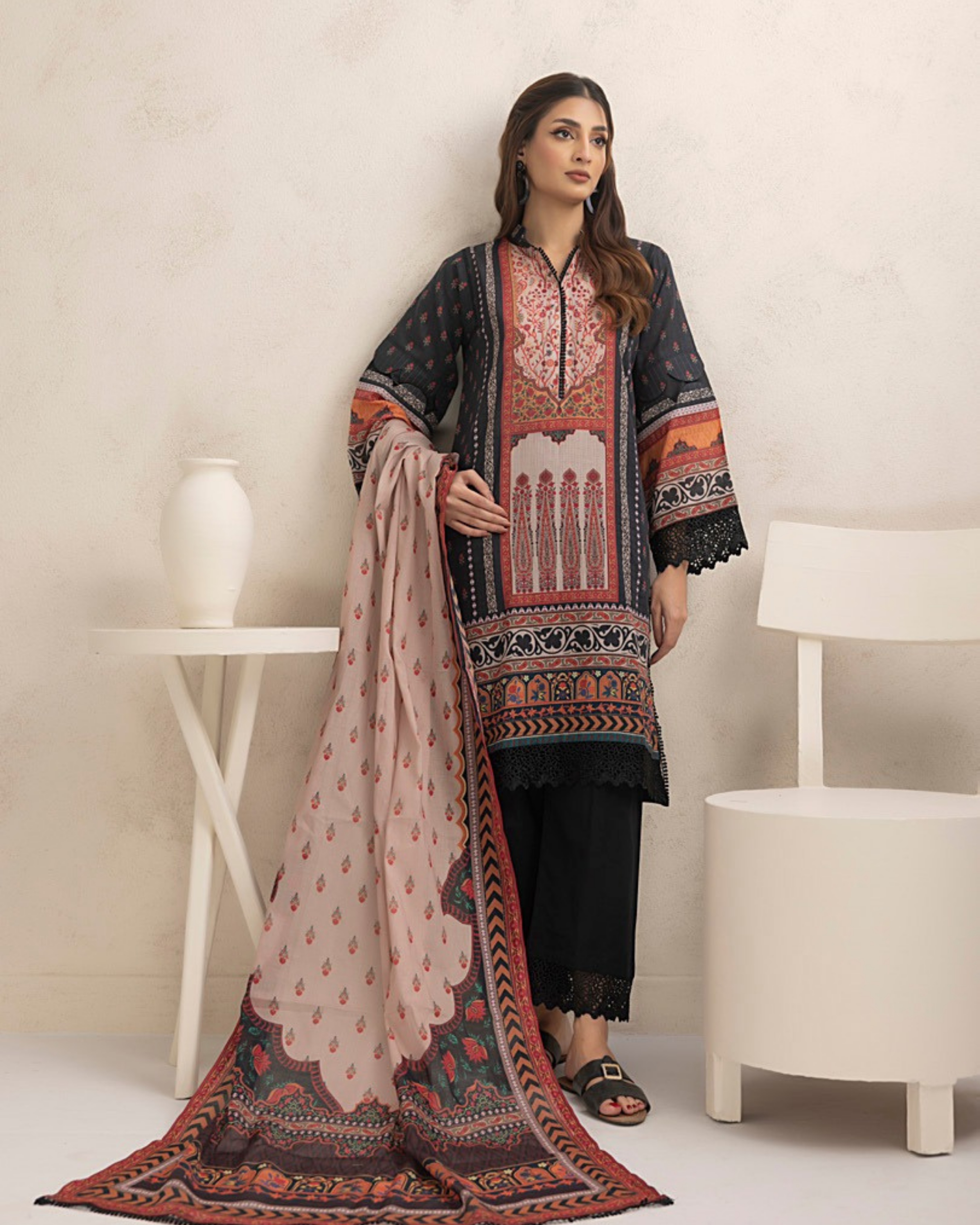 Woman wearing a traditional outfit with a patterned shawl in a minimalistic setting