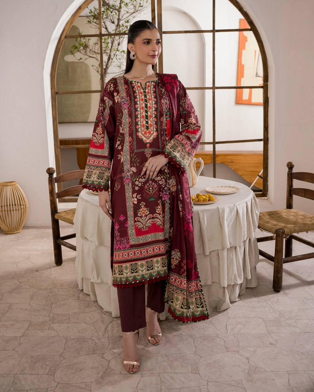 Woman in a patterned dress standing in a room with a mirror and table.