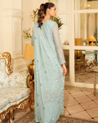 Woman in a light blue saree with a floral pattern in an elegant room.