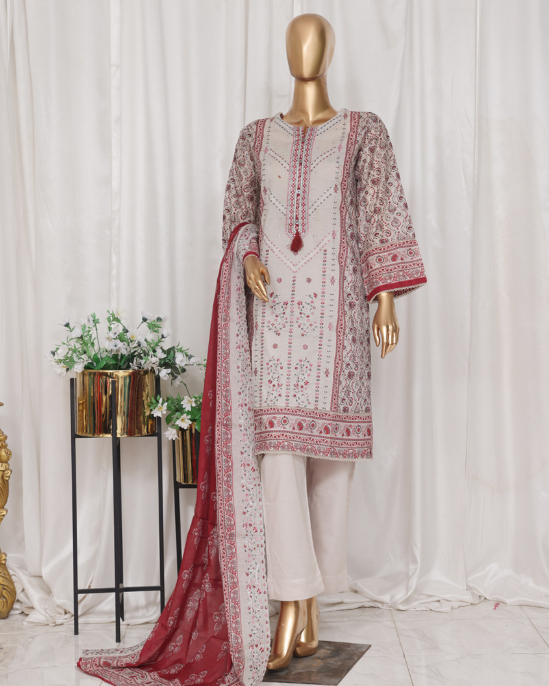Mannequin wearing a traditional outfit with red and white patterns against a white curtain background.