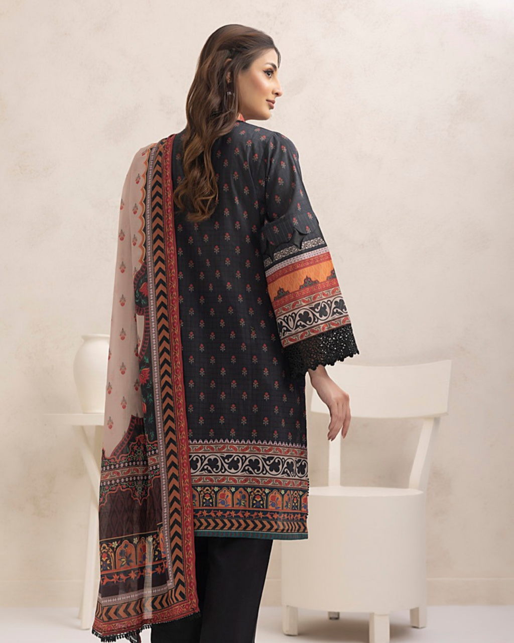 Woman wearing a patterned black shirt with a long scarf in a minimalistic setting