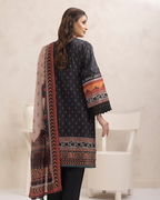Woman wearing a patterned black shirt with a long scarf in a minimalistic setting