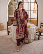Woman in an embroidered traditional outfit standing in a room with a table and chairs.