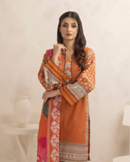 Woman wearing an orange and patterned dress against a plain background