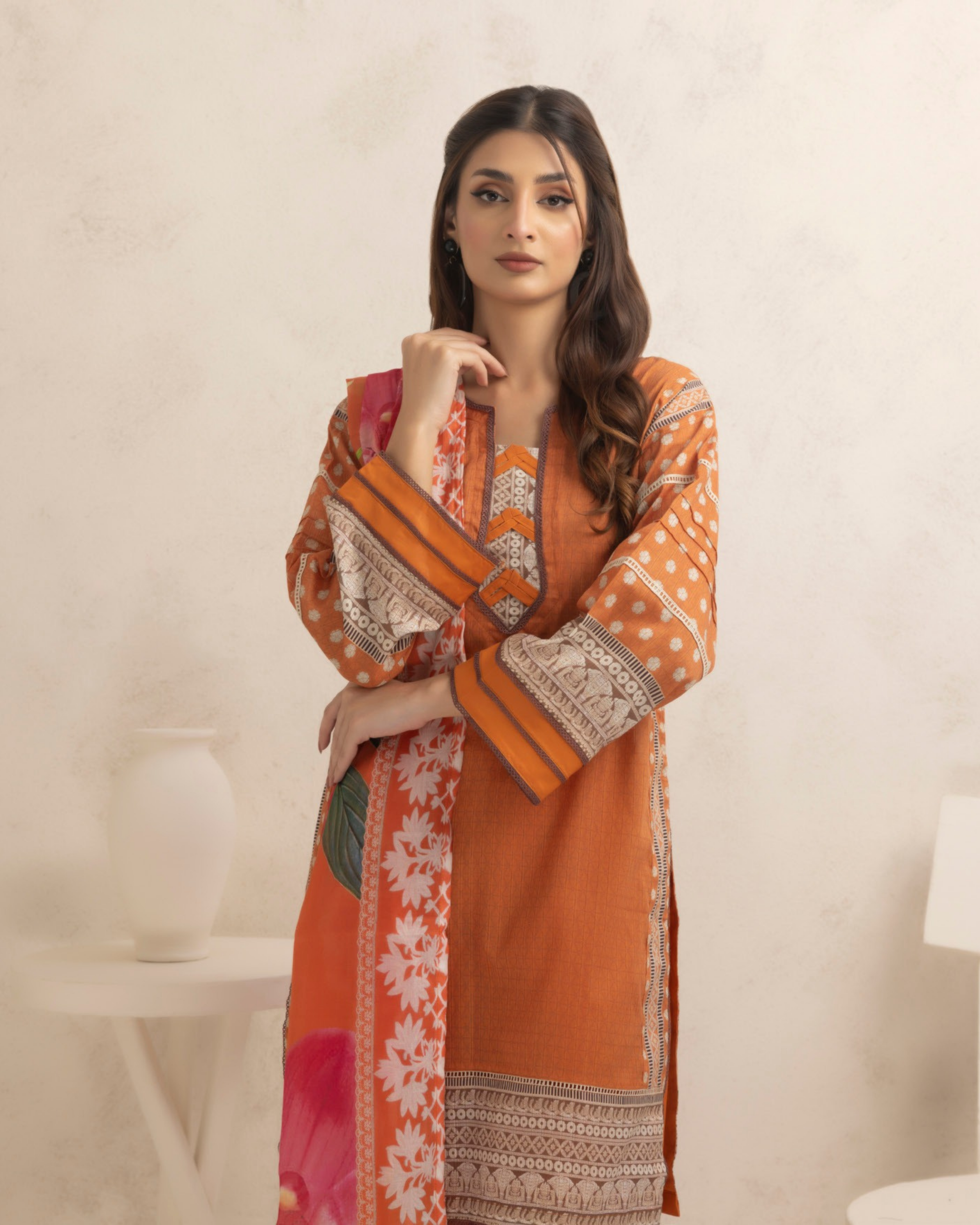 Woman wearing an orange and patterned dress against a plain background