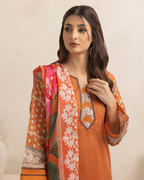 Woman wearing an orange floral dress with a matching dupatta on a beige background