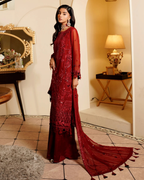 Woman in a red embroidered dress standing in a decorated room.