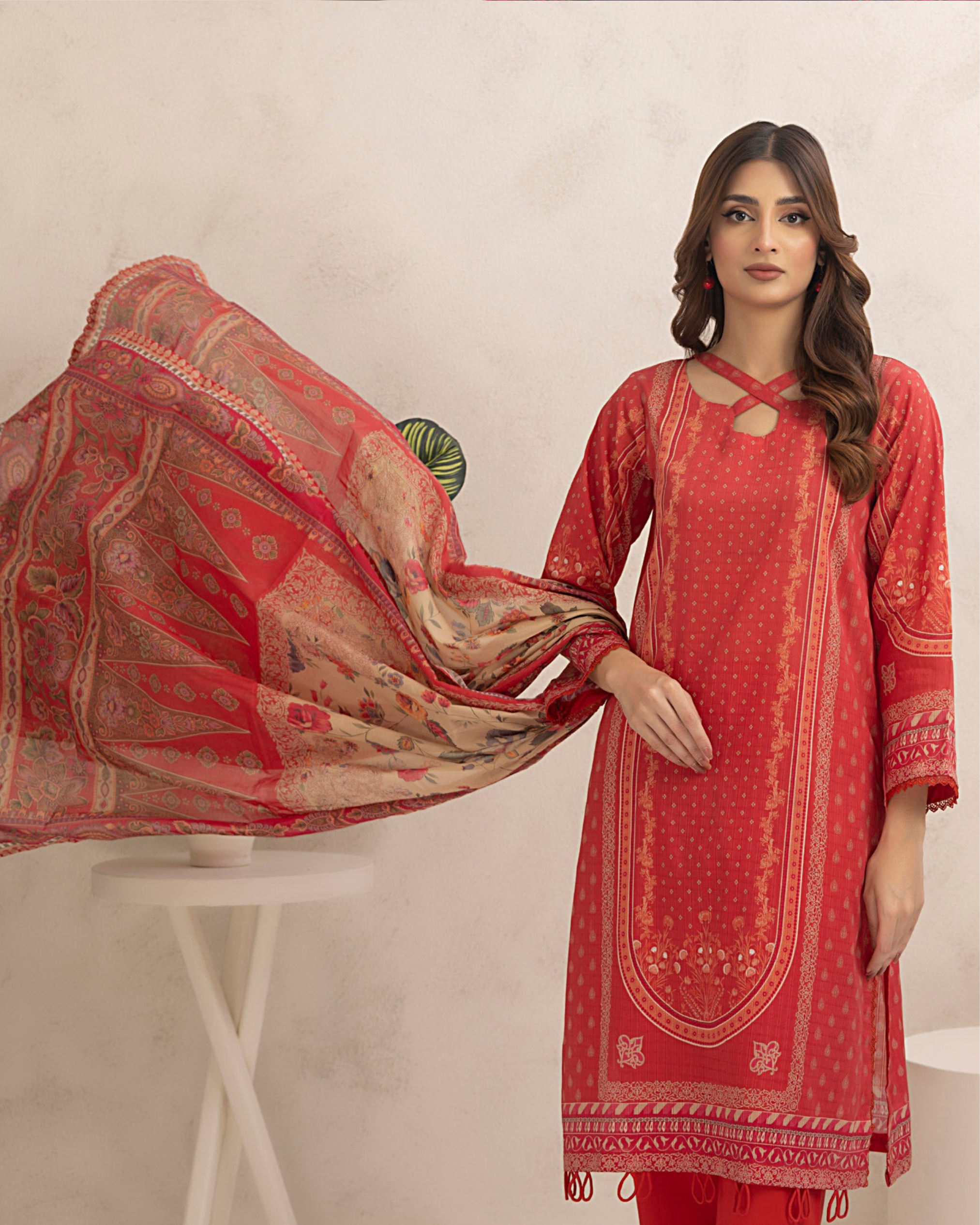 Woman wearing a traditional outfit with a patterned dupatta in a minimalistic setting.