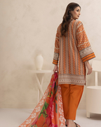 Woman wearing an orange and brown traditional outfit with a matching dupatta in a minimalistic room.