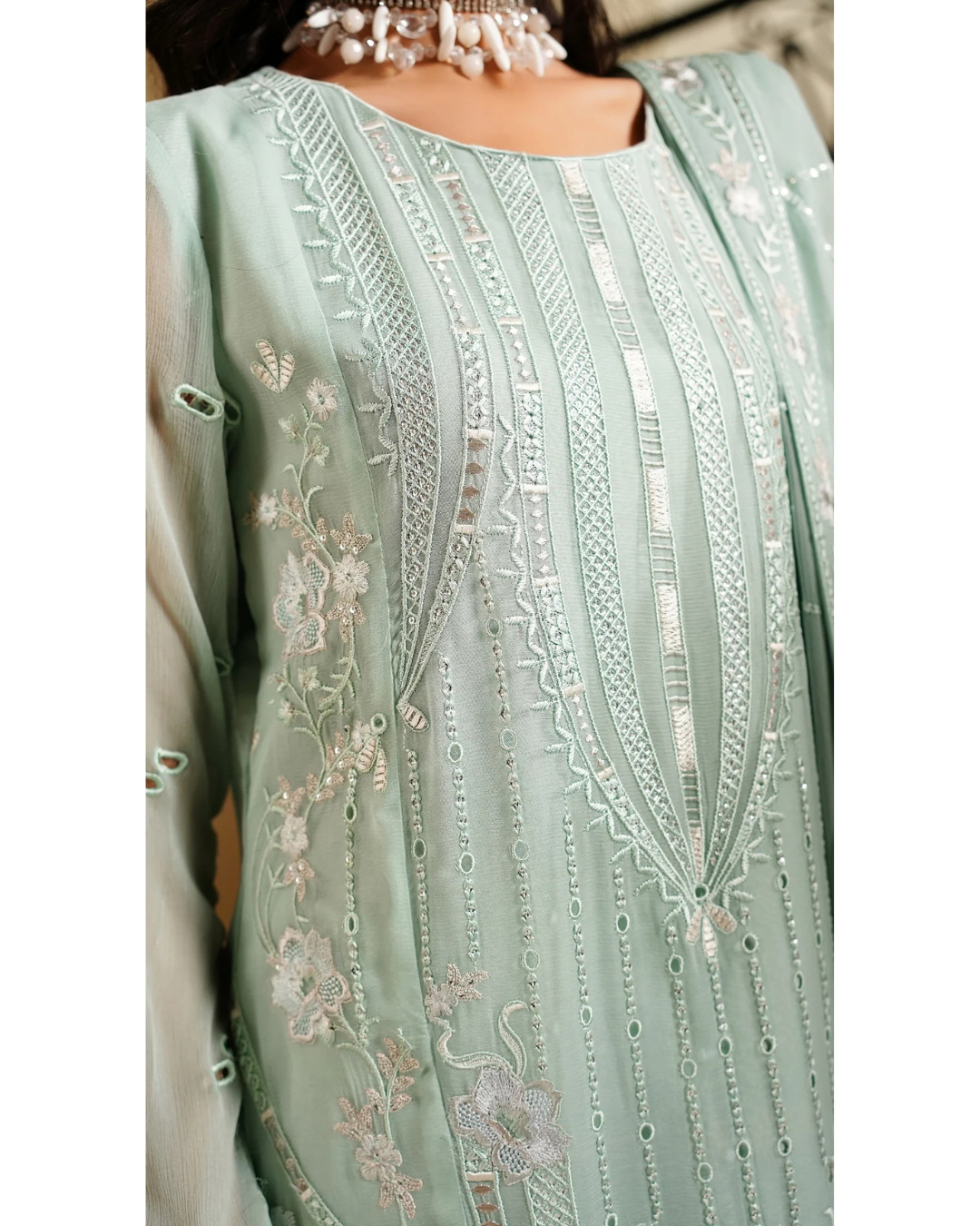 Light green embroidered garment with intricate patterns on a plain background
