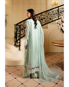 Woman in a light green traditional outfit standing in an elegant interior setting.