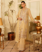 Woman in a beige embroidered outfit standing in an elegant room with decorative elements.