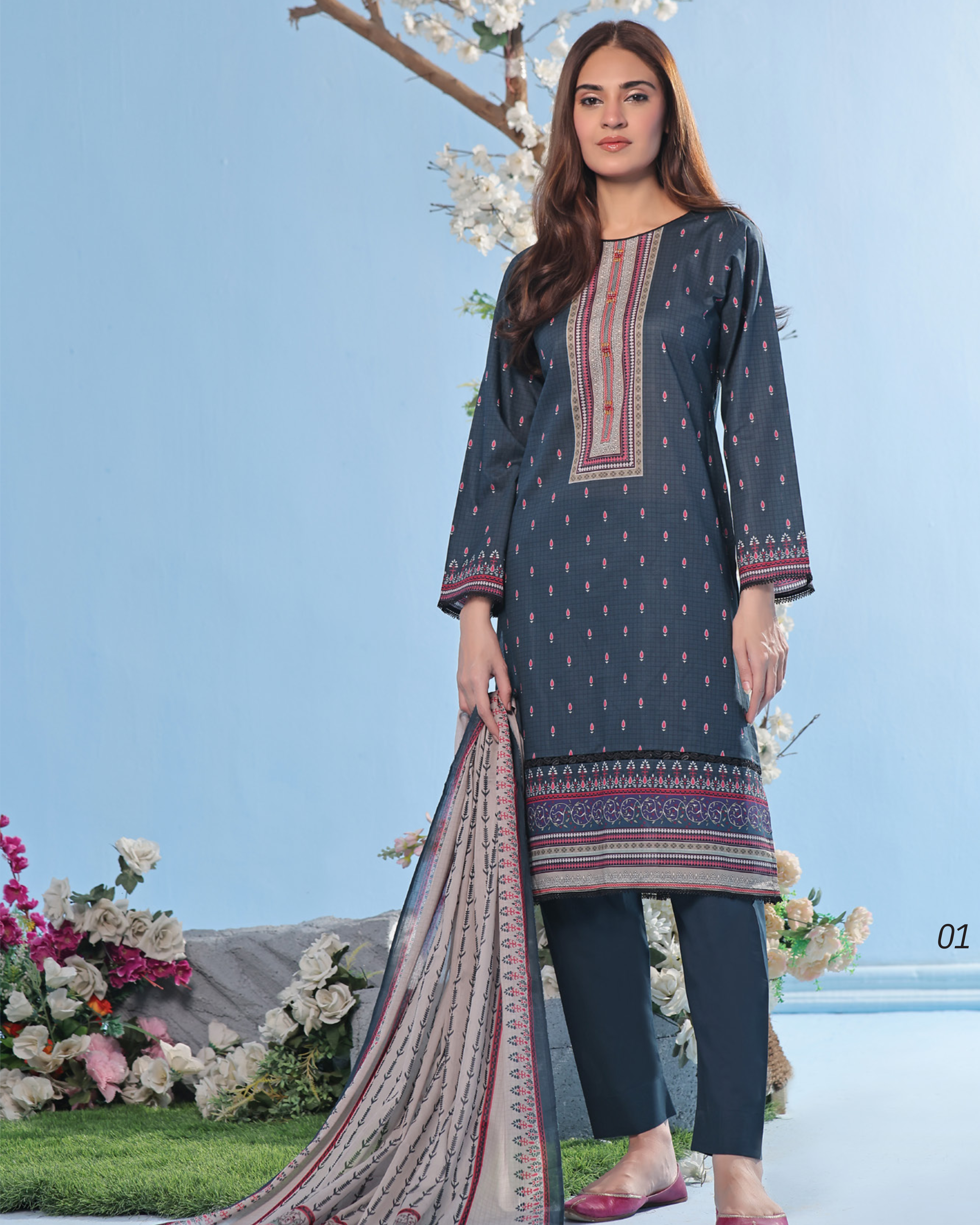 Woman wearing a dark blue embroidered kurta with pants and dupatta against a light blue background.