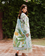 Woman wearing a floral and leaf-patterned dress standing outdoors with greenery in the background