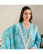 Woman wearing a light blue embroidered traditional outfit with a neutral background