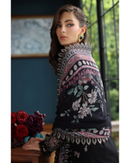 Woman wearing a black embroidered shawl with floral patterns in an indoor setting.