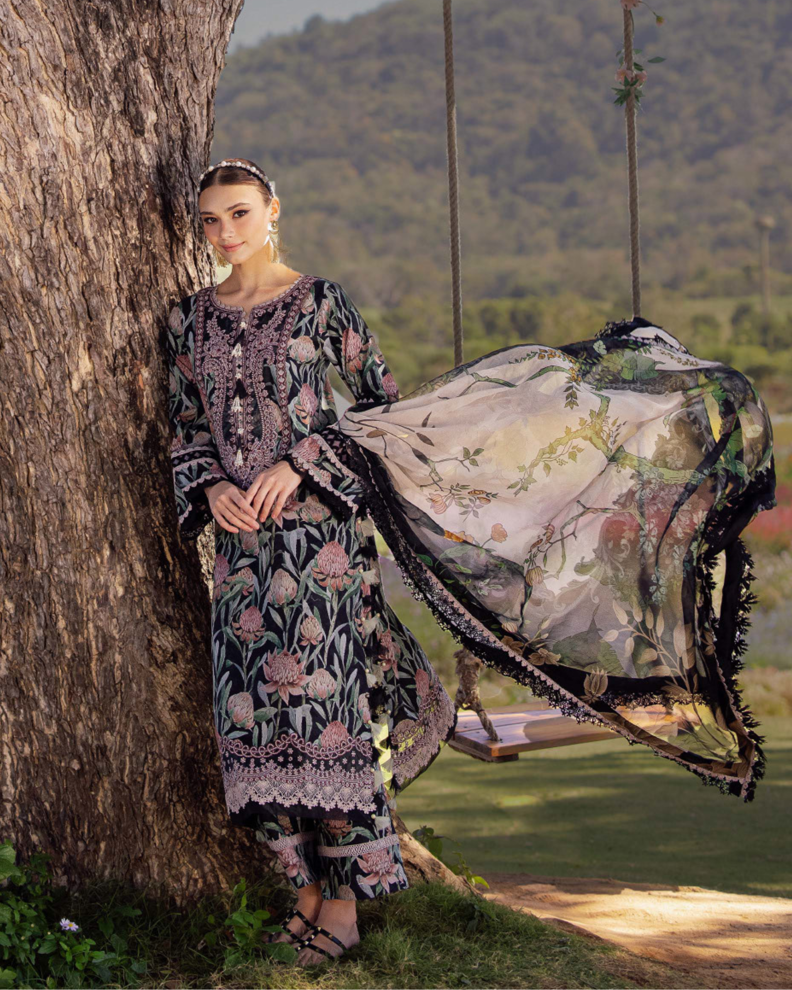 Woman in a floral dress standing next to a tree with a scenic background