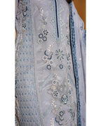 White embroidered garment with blue floral patterns on a plain background