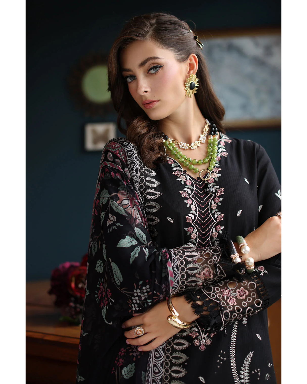 Woman wearing a black patterned outfit with jewelry indoors.