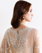 Woman wearing a beige embroidered dress with a white background