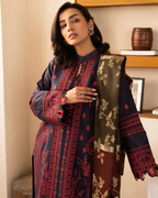 Woman wearing a dark blue embroidered outfit with a matching shawl indoors.