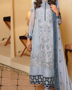 Woman wearing a light blue embroidered dress with a matching dupatta indoors.