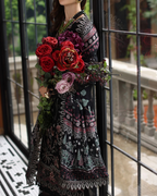 Mannequin wearing a patterned dress with a bouquet of flowers in front of a glass door.